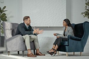 Interview or talk between a man and a woman sitting in armchairs